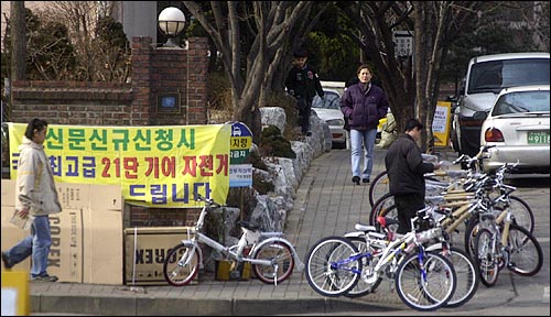 1월 20일 서울 광진구 구의동 아파트 단지입구에서 '신문 신규 신청시 국산 최고급 21단 기어 자전거를 드립니다'라는 현수막을 걸어 놓고 신문 판촉활동을 벌이고 있다. 